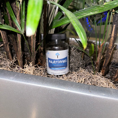 NutriWell Joint Support Gummy Bottle amidst green plants at Emory University Hospital, Atlanta, Georgia.