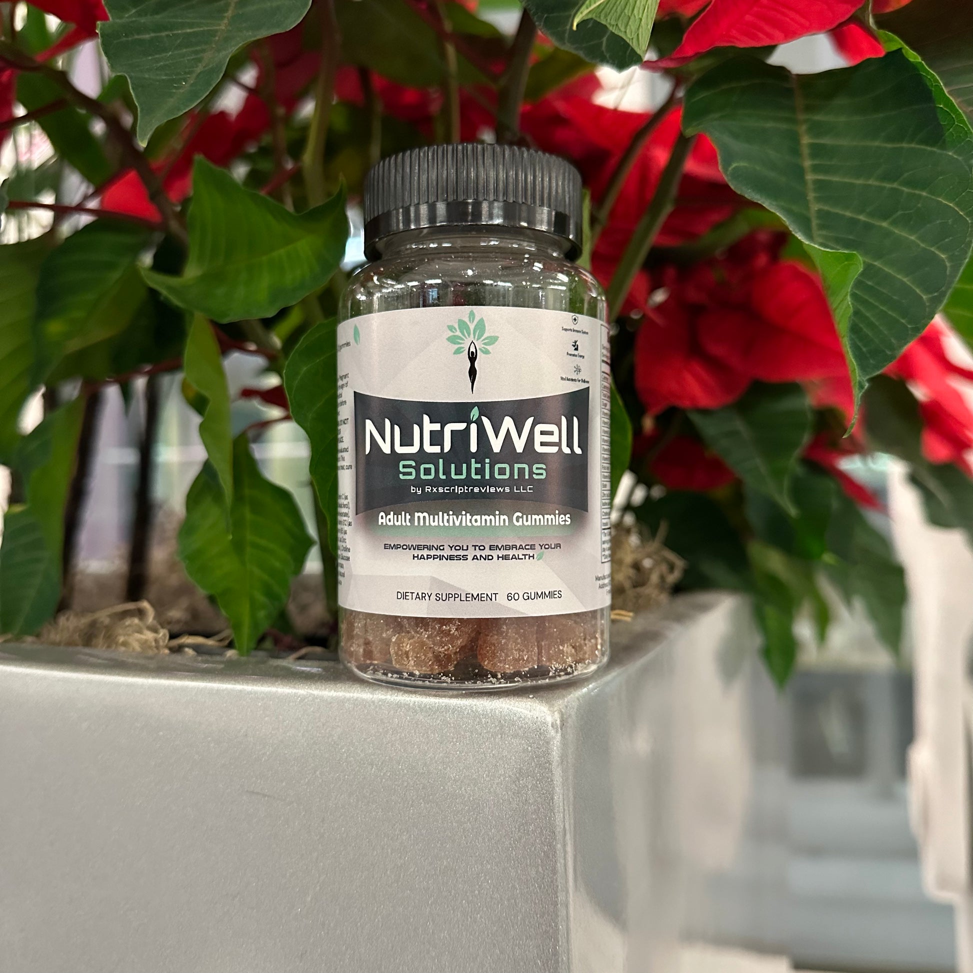 NutriWell Multivitamin Gummy Bottle amidst red and green plants at Emory University Hospital, Atlanta, Georgia.